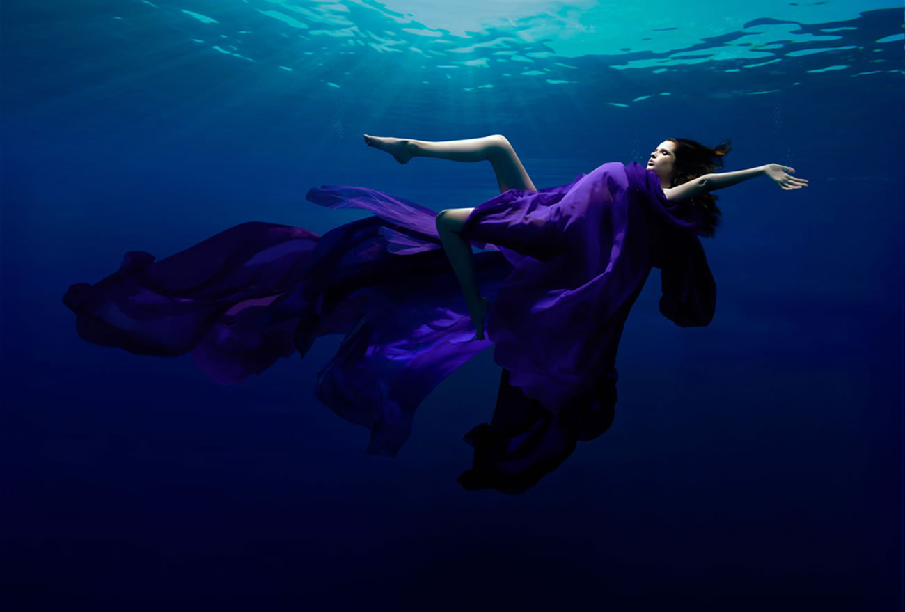 woman underwater, purple dress, photography by Patrick Curtet