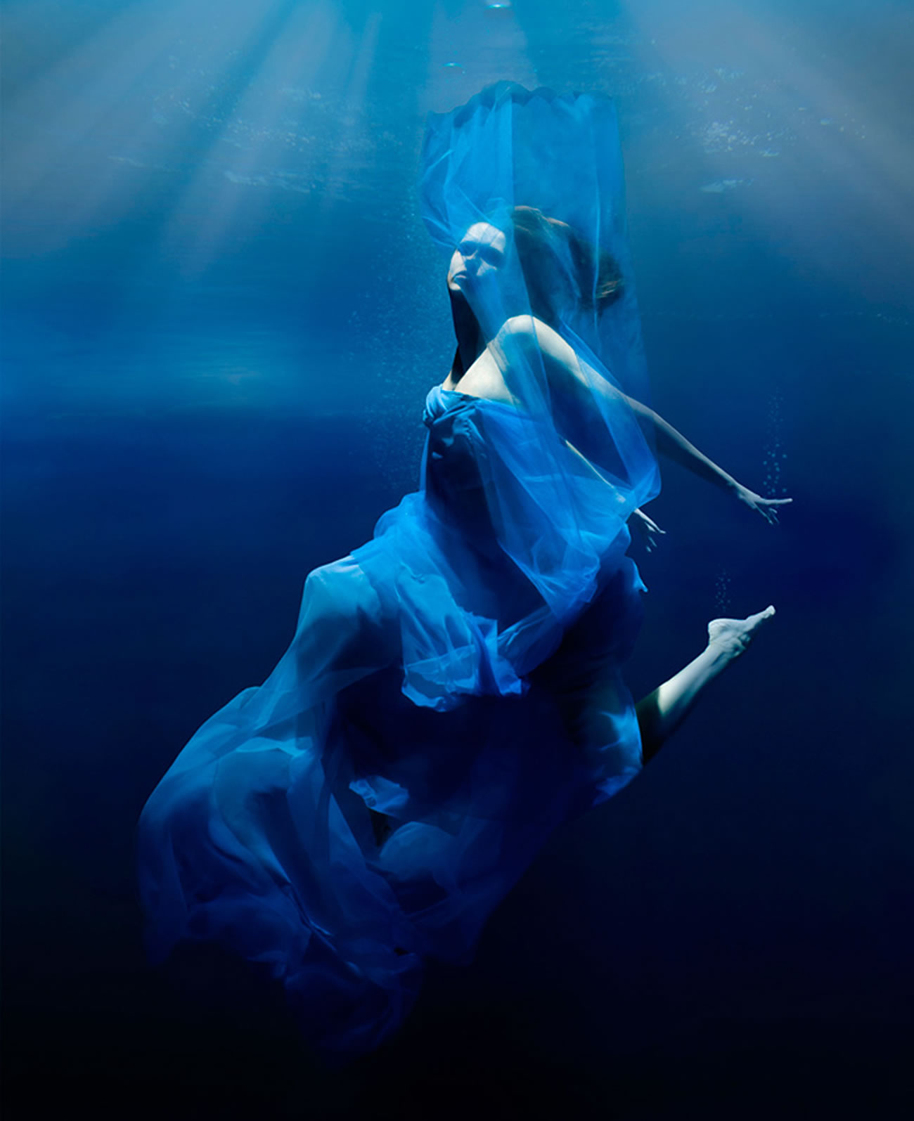 woman underwater, blue dress, photography by Patrick Curtet