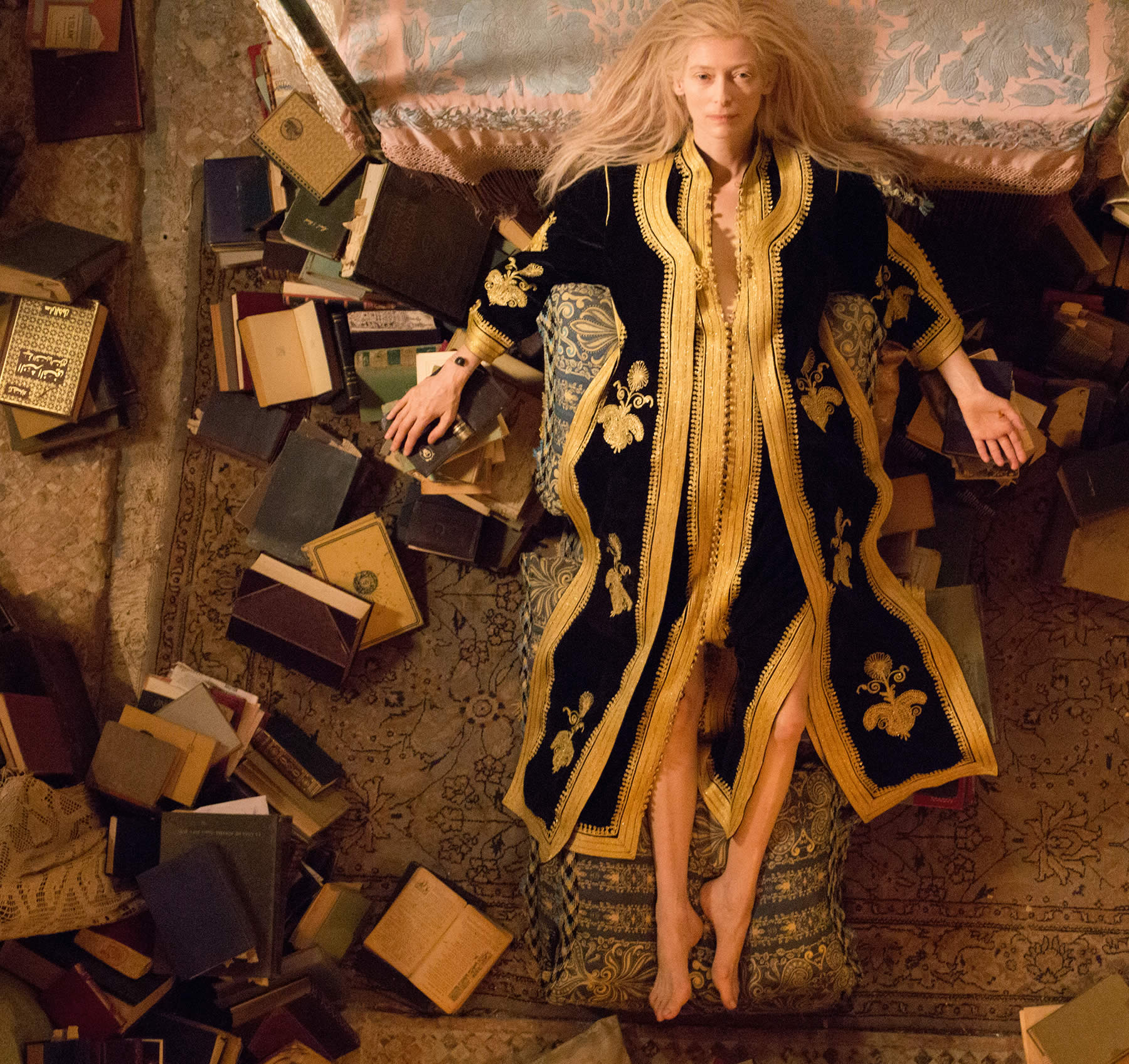 Tilda lying down with books all around, in the only lovers left alive