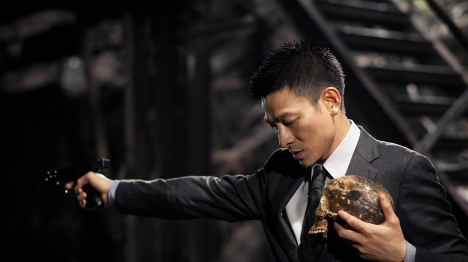 actor holding a human skull and with gun in other hand, blind detective