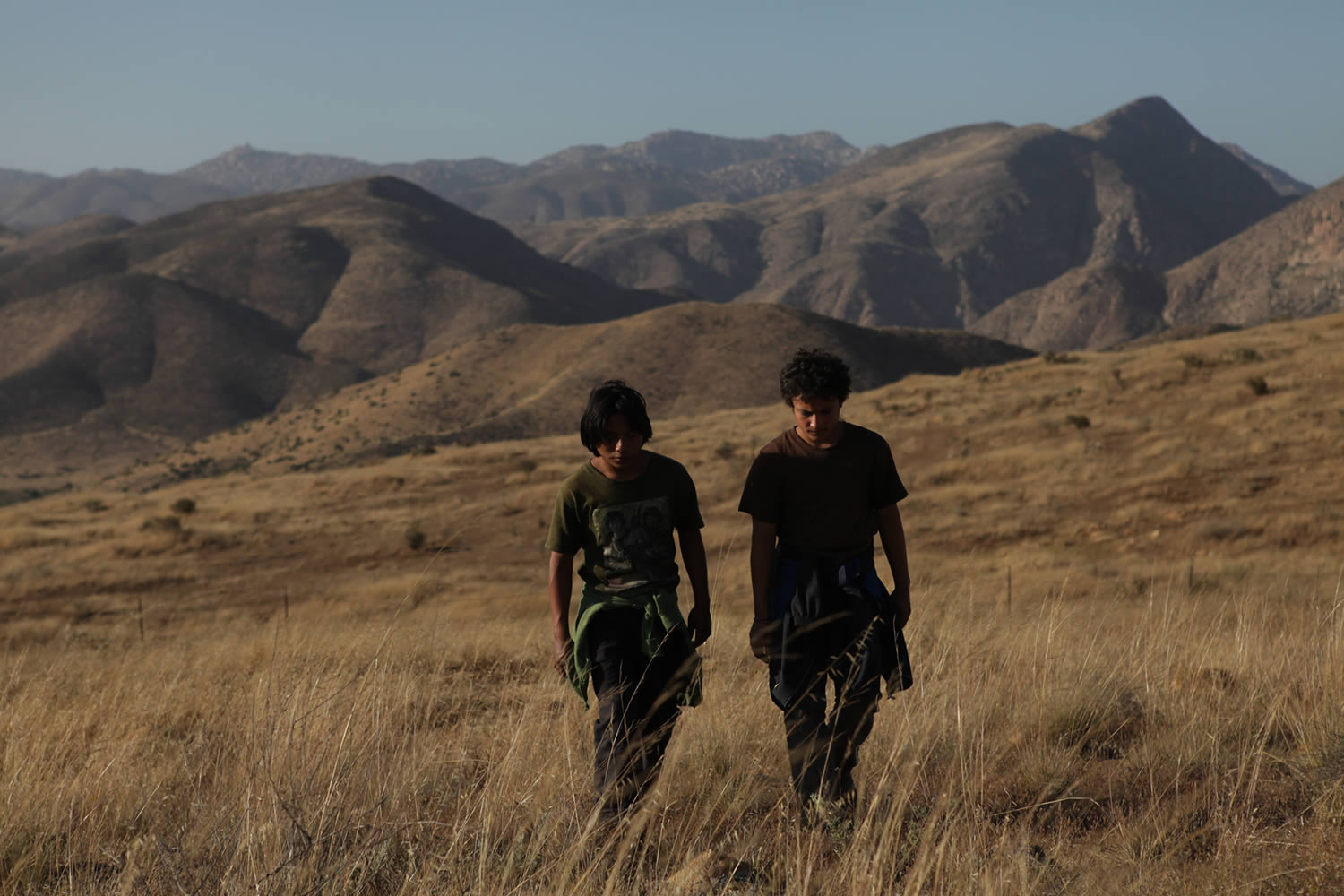 two kids walking in field with mountains in back, La Jaula de Oro