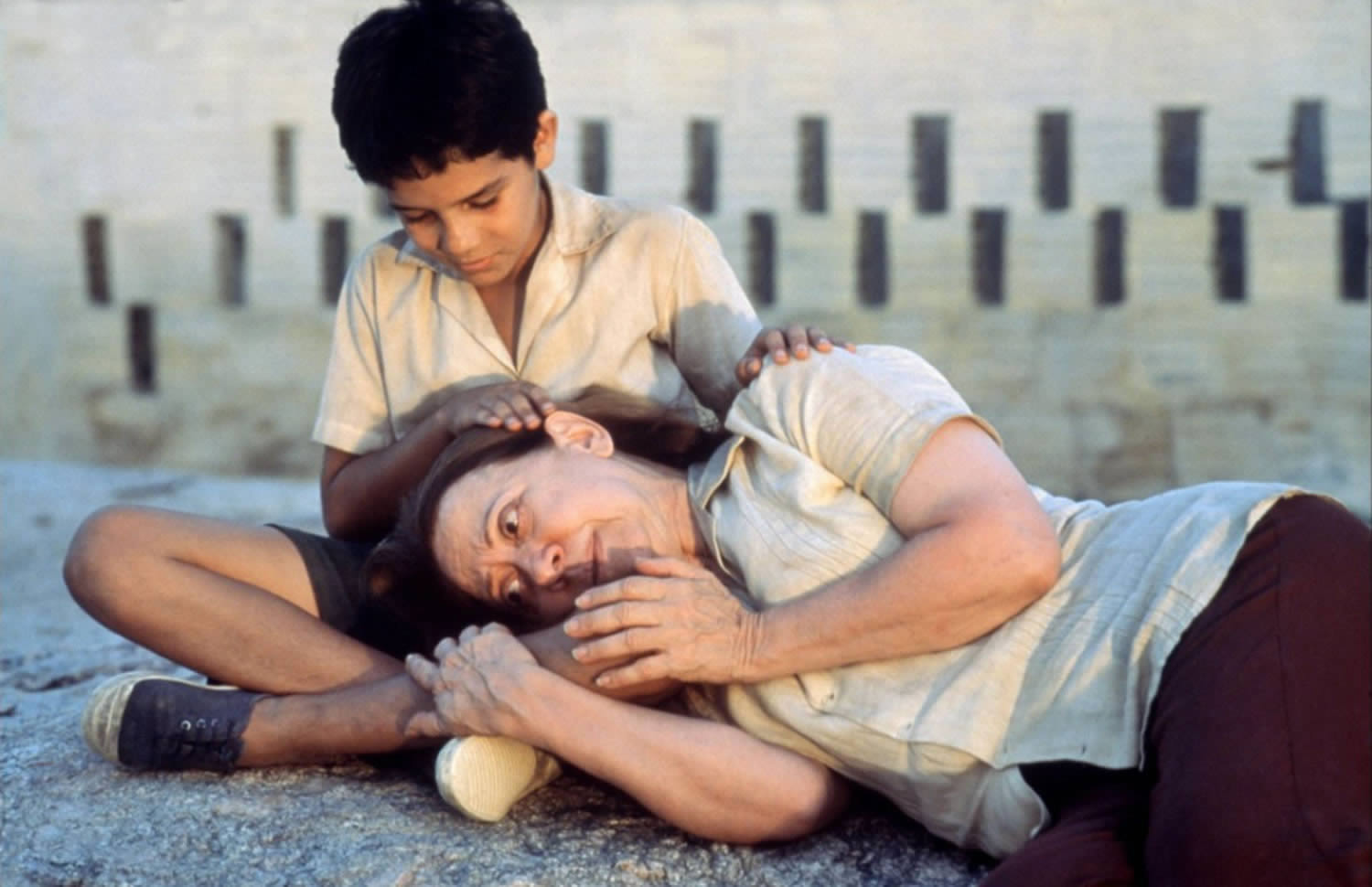 child embracing woman who is lying on the ground, in Central Station movie