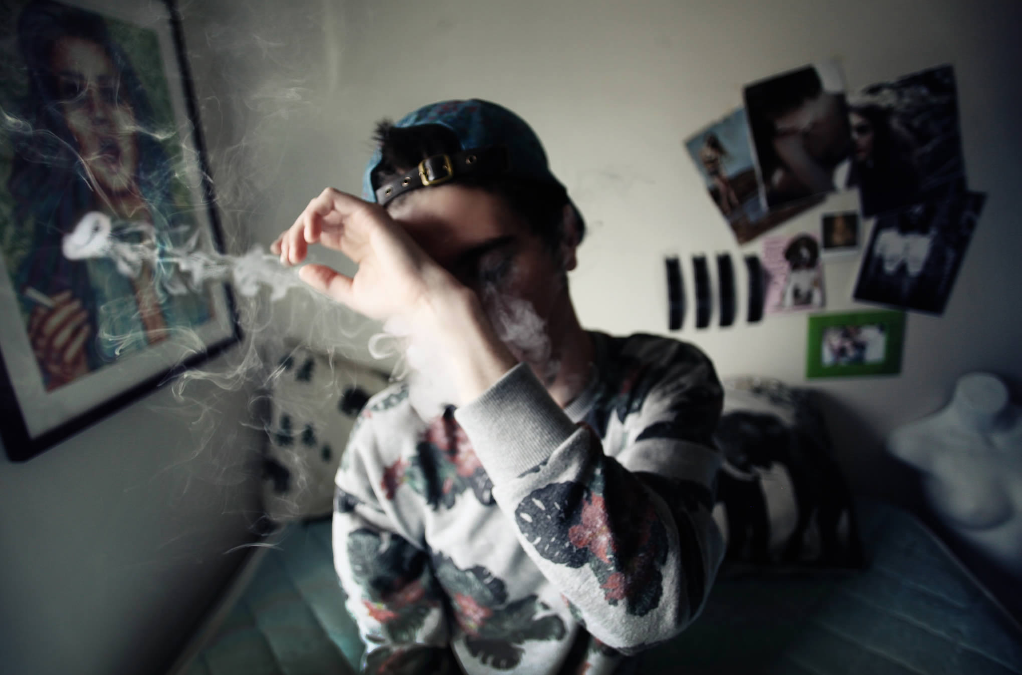 guy wearing cap and smoking, in bedroom