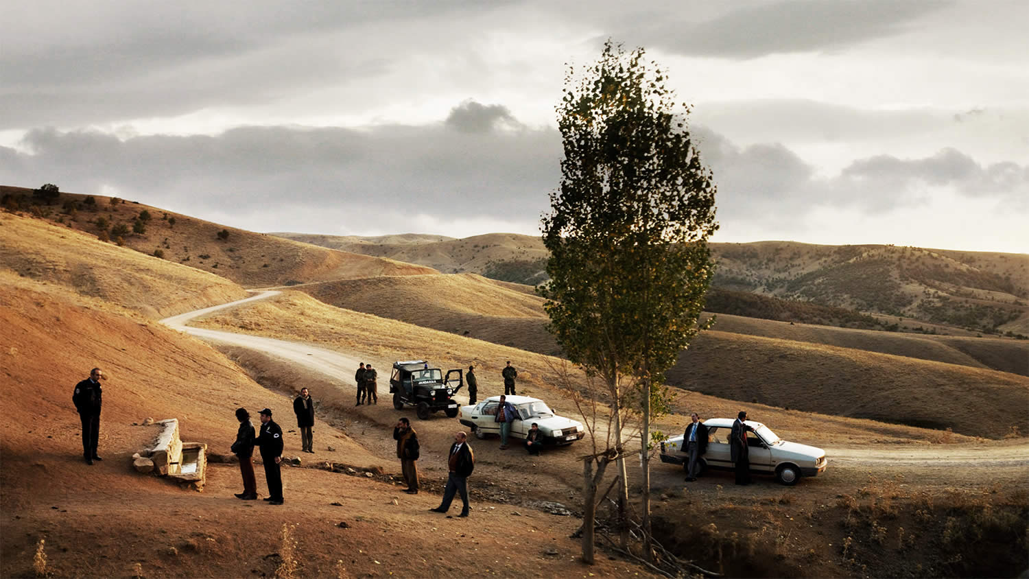 cars and men in field, in Once Upon a Time in Anatolia