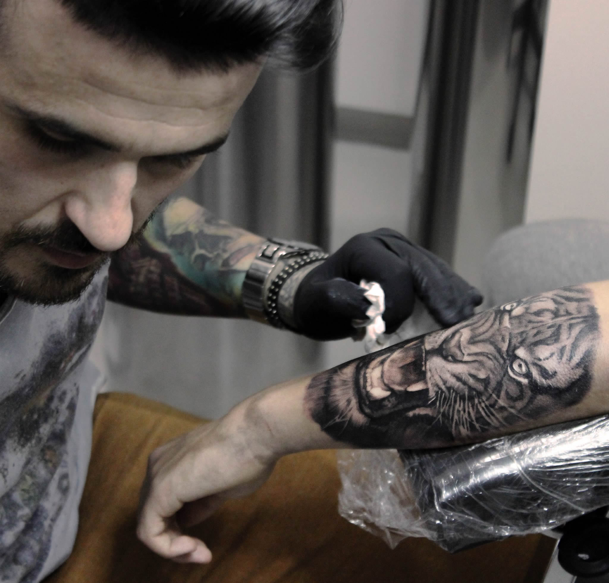 the artist dave paulo working on a tiger tattoo