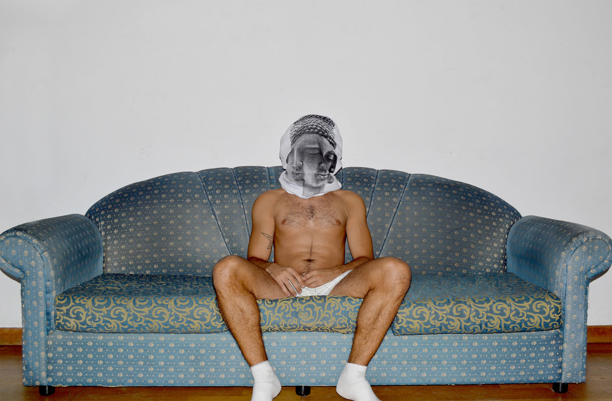 man with tshirt over head, sitting on couch