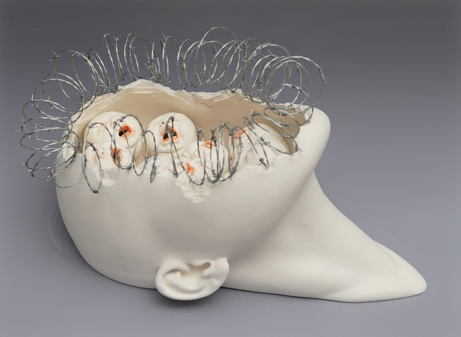 face busted open with babies inside, sculpture