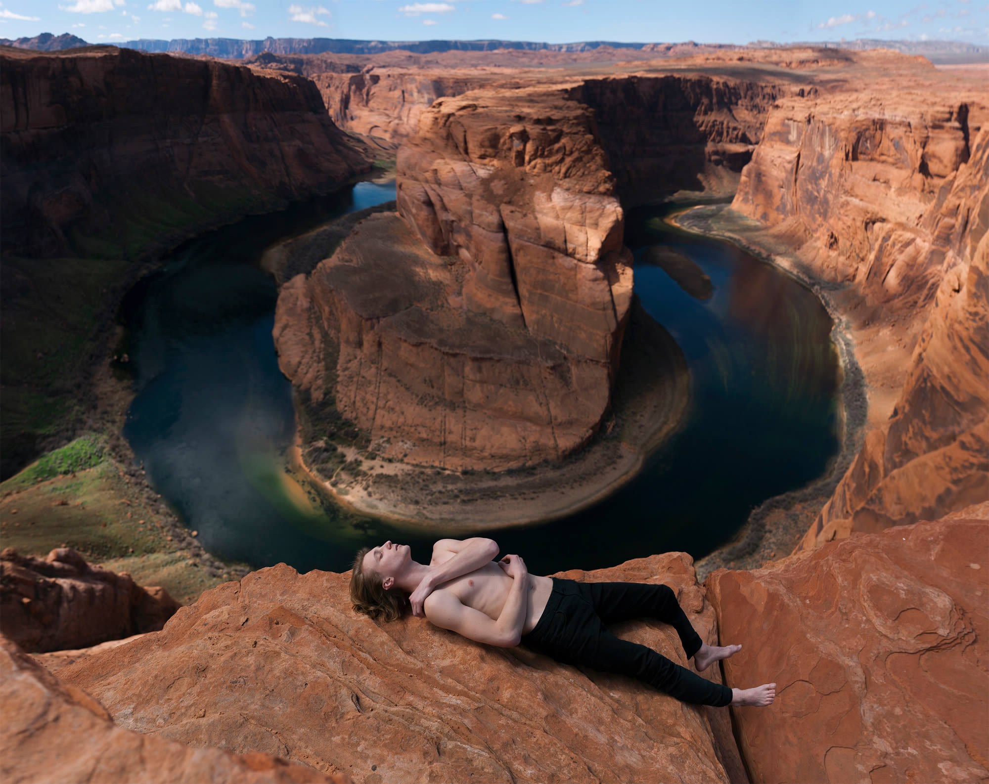 man lying on cliff, canyon in the background. photography