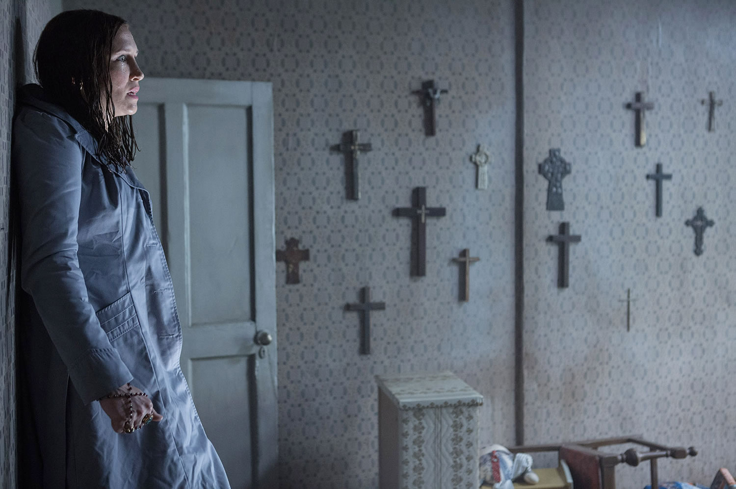 woman leaned on wall, crosses on wall, the conjuring 2