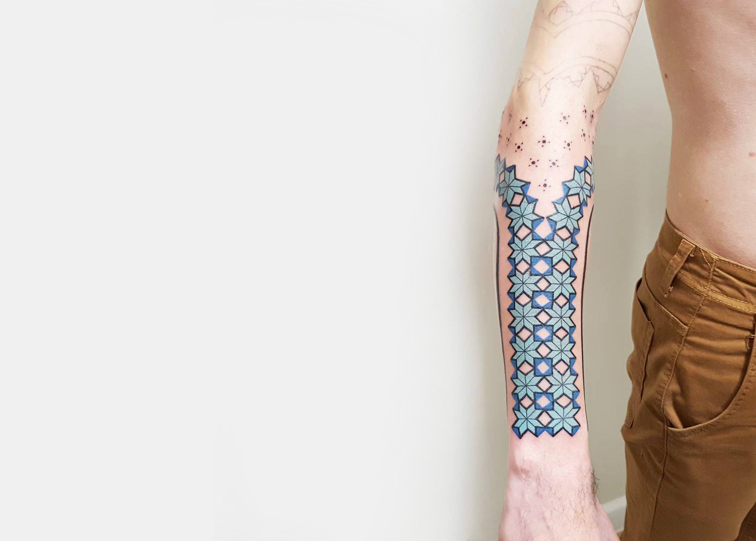 Brian Gomes blue geometric forearm tattoo