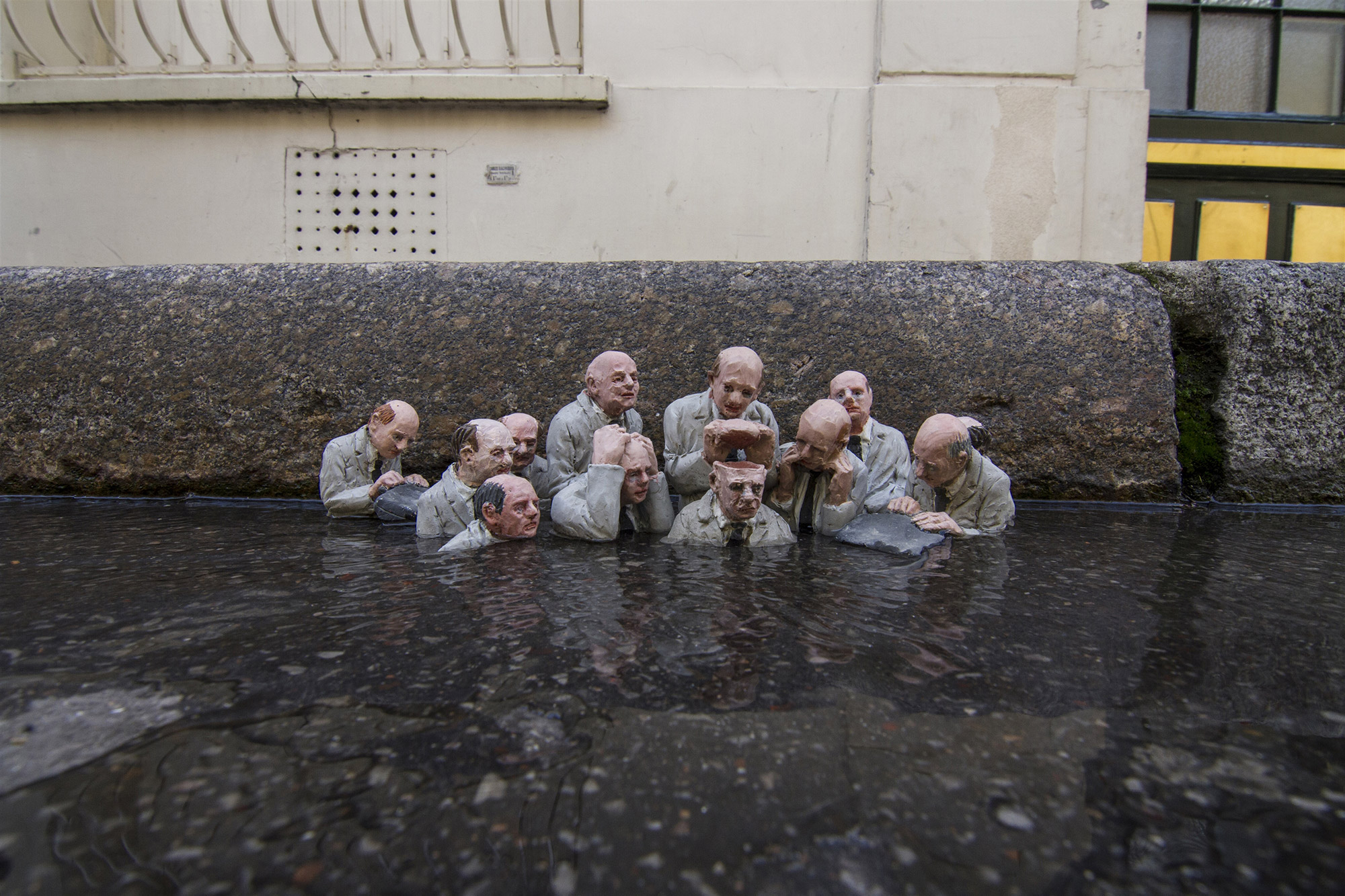 Isaac Cordal - group of men in puddle