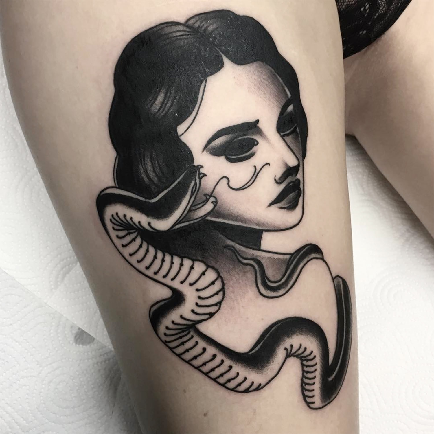 snake and woman, portrait tattoo on thigh, black ink