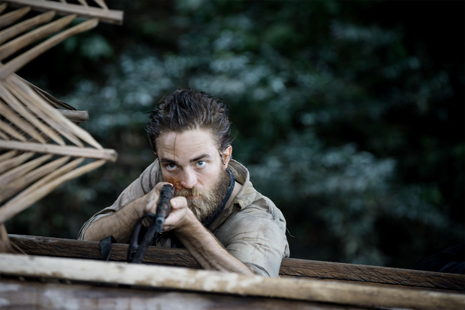 Robert Pattinson holding a rifle in the lost city of z