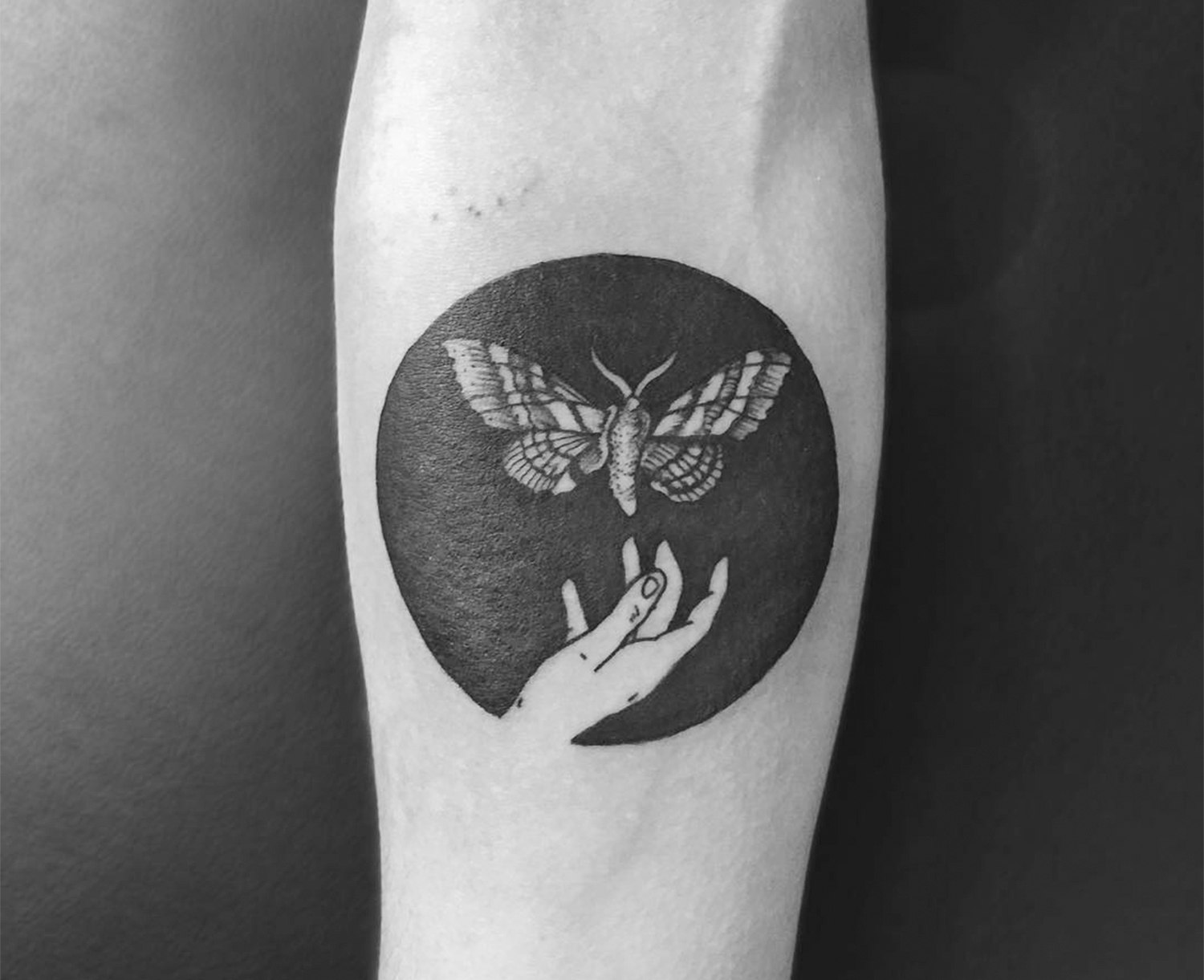 hand and moth, negative space tattoo by Tomtom Tattoos