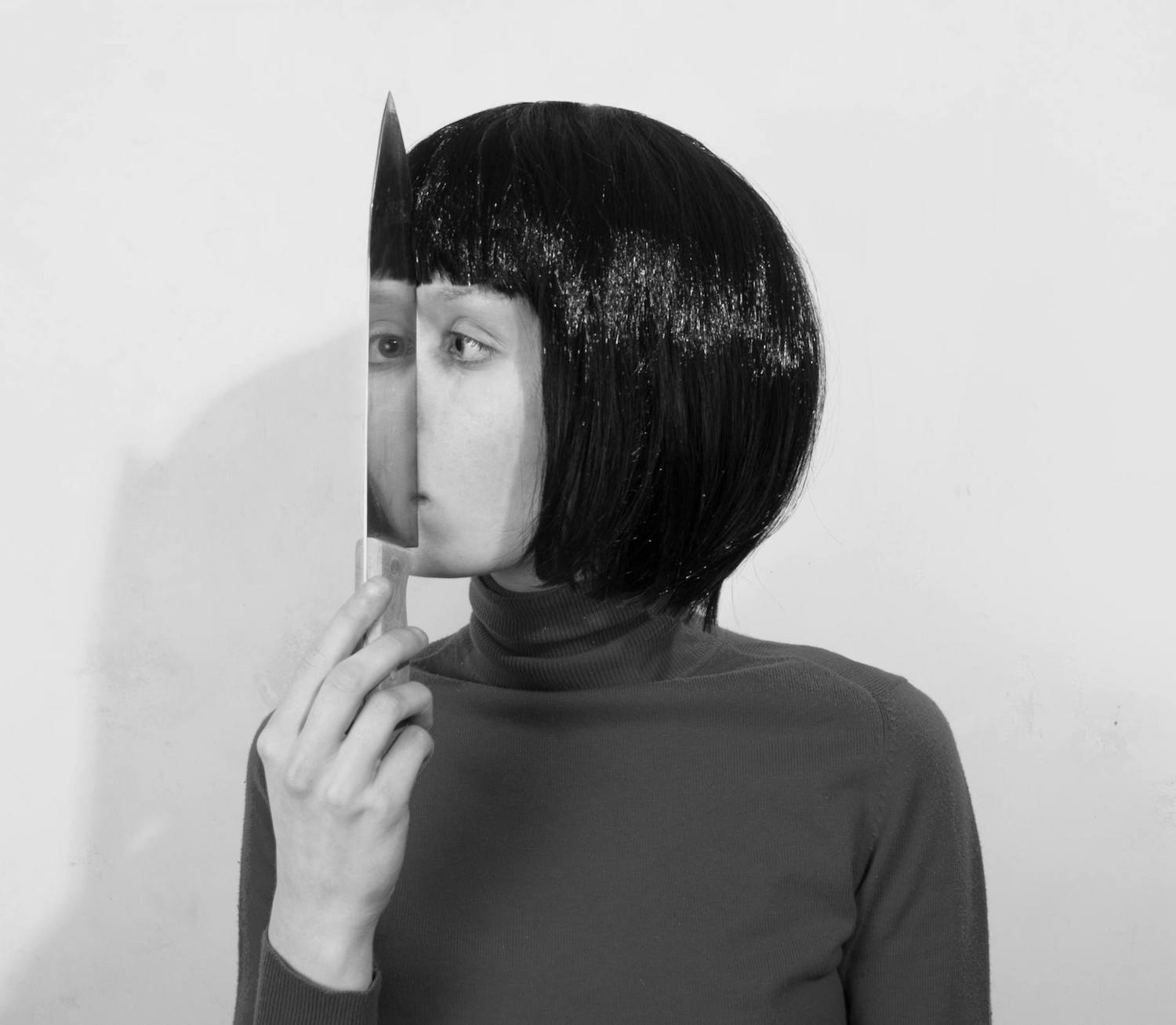 woman looking at her reflection in a knife mirror