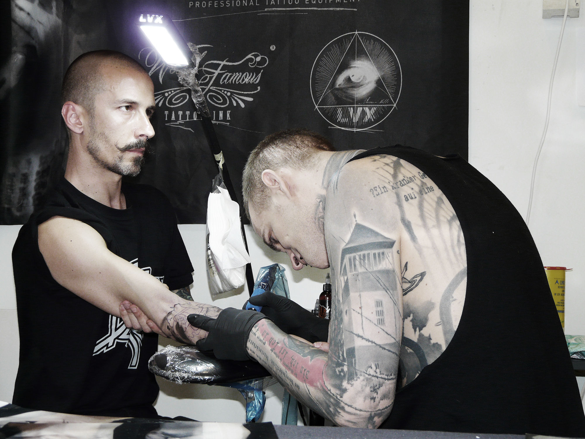 Neon Judas tattooing client at a tattoo convention