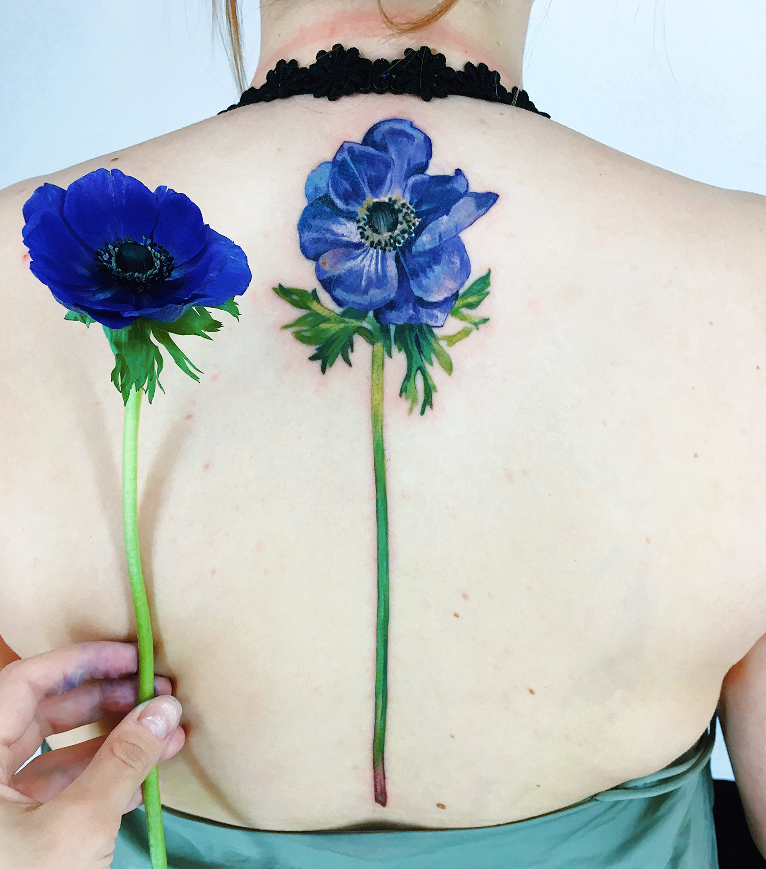 blue flower tattoo on back, live leaf