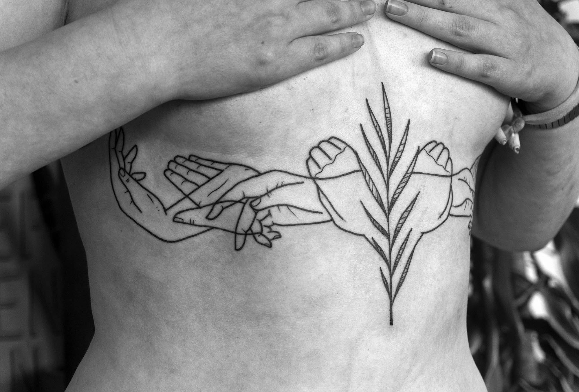 Line drawing hands on stomach tattoo