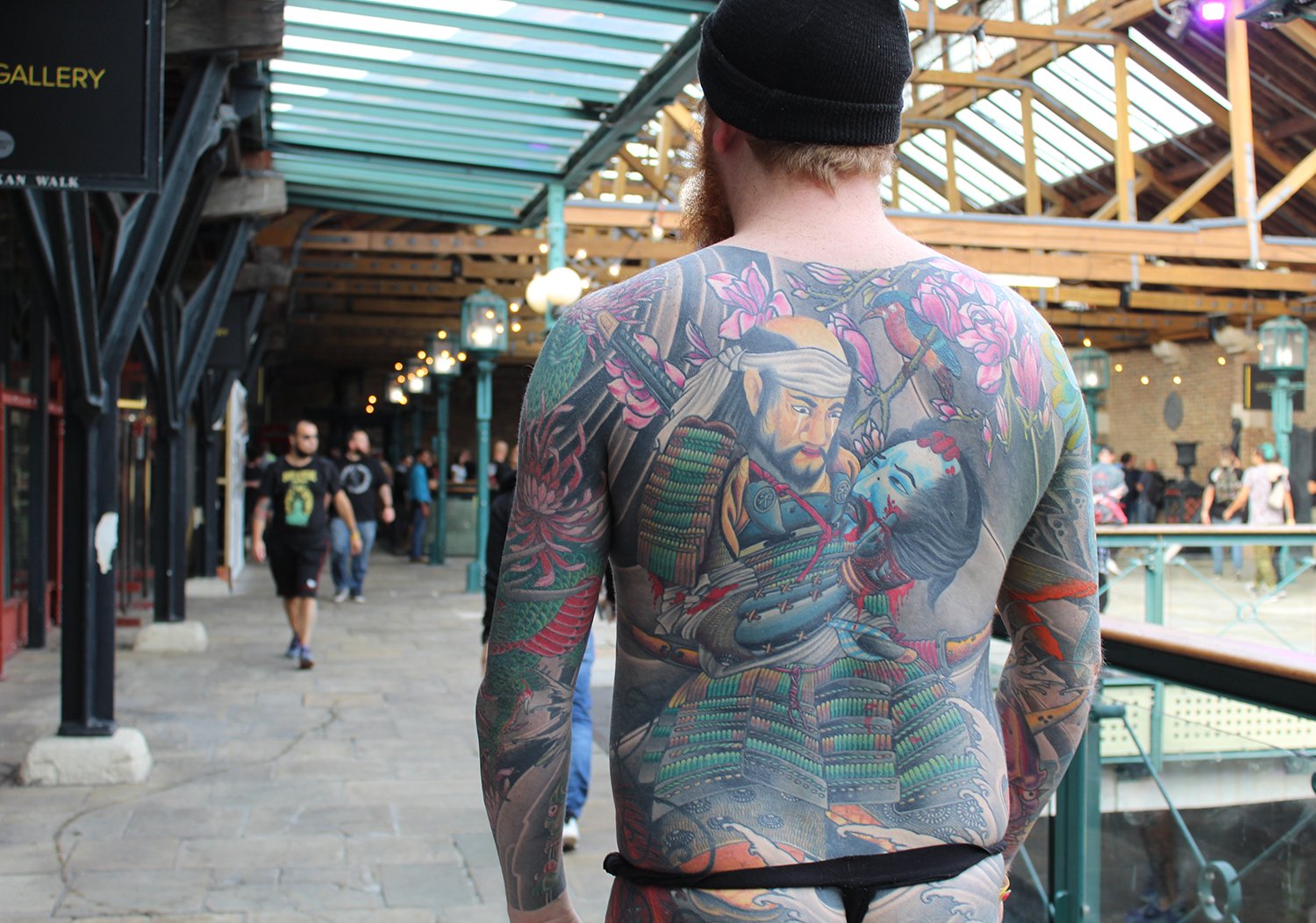 spectator with asian style tattoo on back, at convention