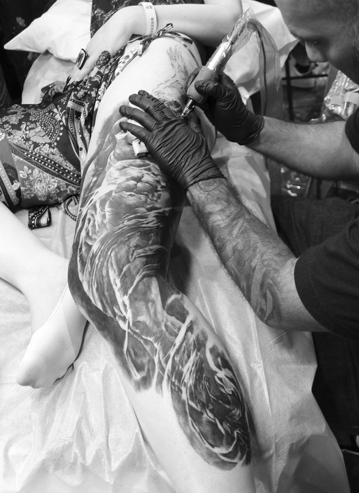 carlos torres tattooing a leg, realism tattoo, black and grey