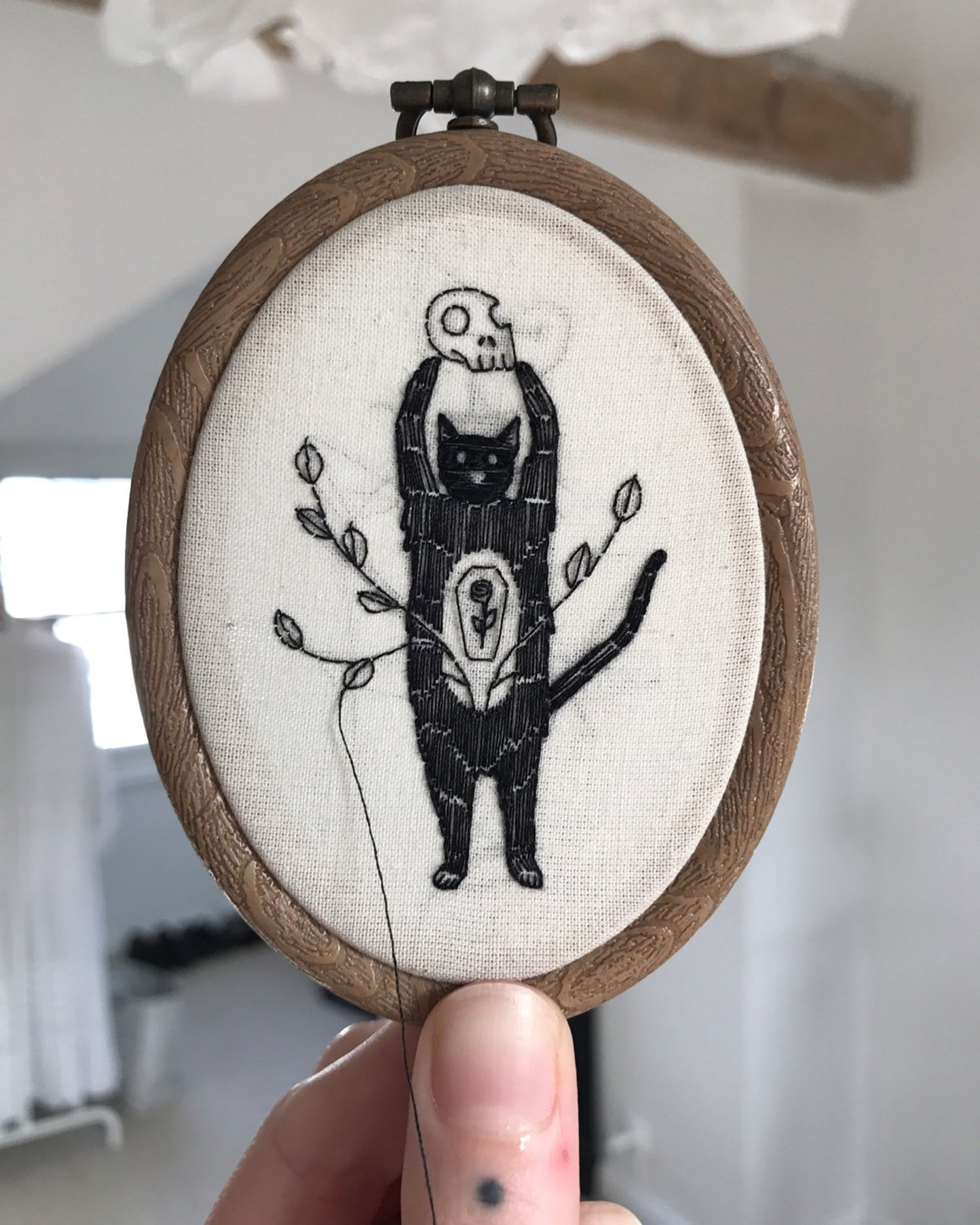 Embroidery of a cat holding a skull