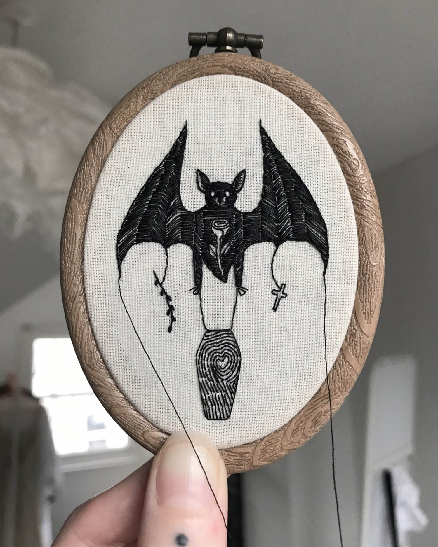Embroidery of a bat holding a coffin