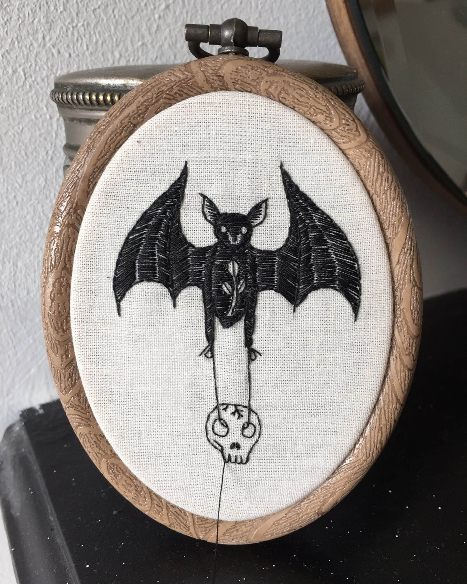 Embroidery of a bat holding a skull