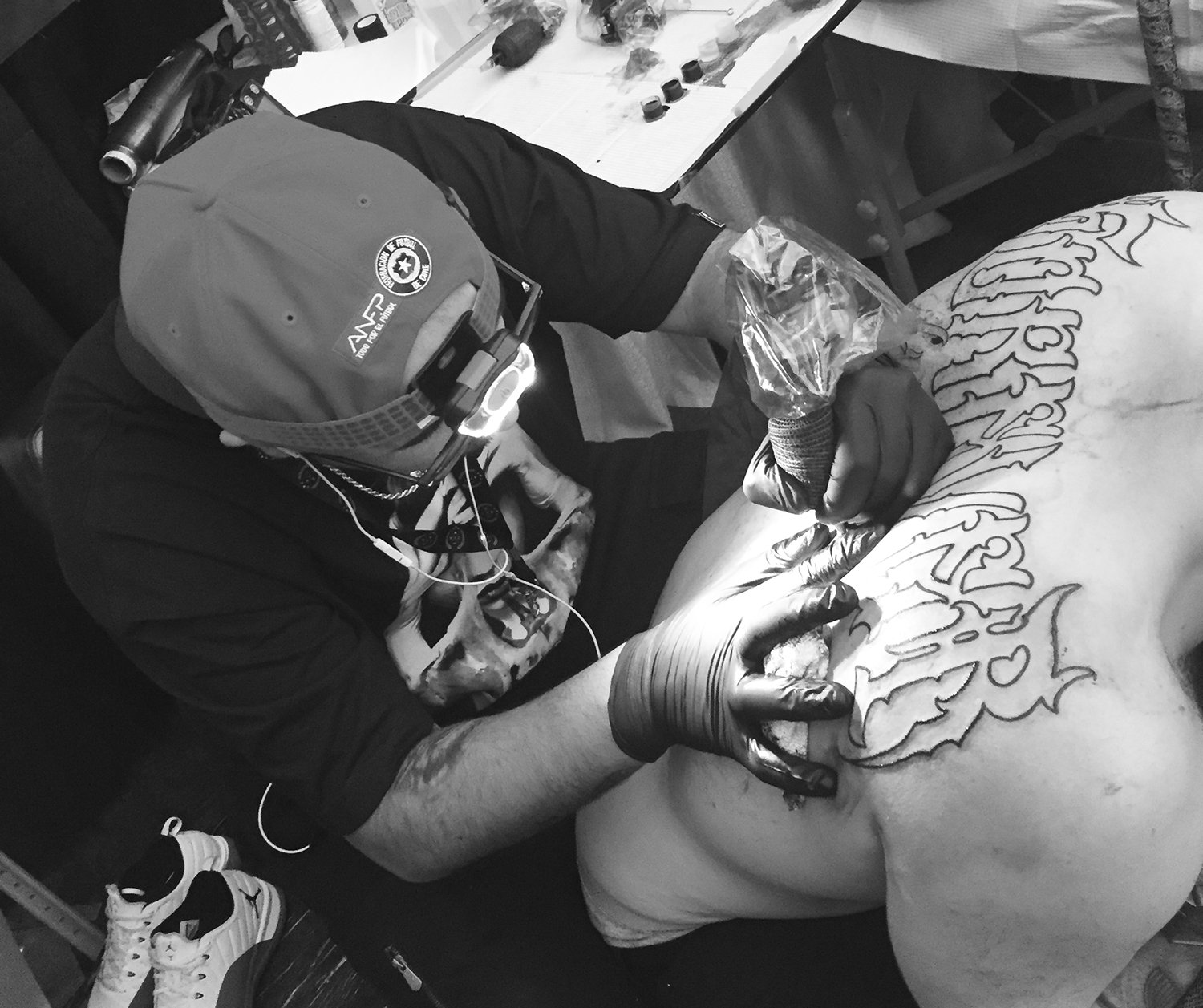 getho tattooing a large script piece on back, tattoo conventions