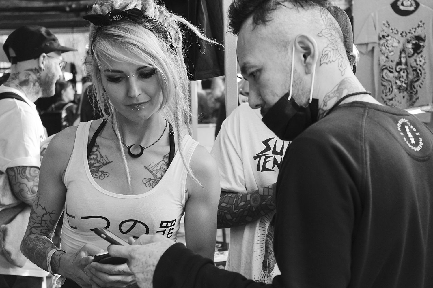 Nissaco showing mobile phone to a spectator, london tattoo convention