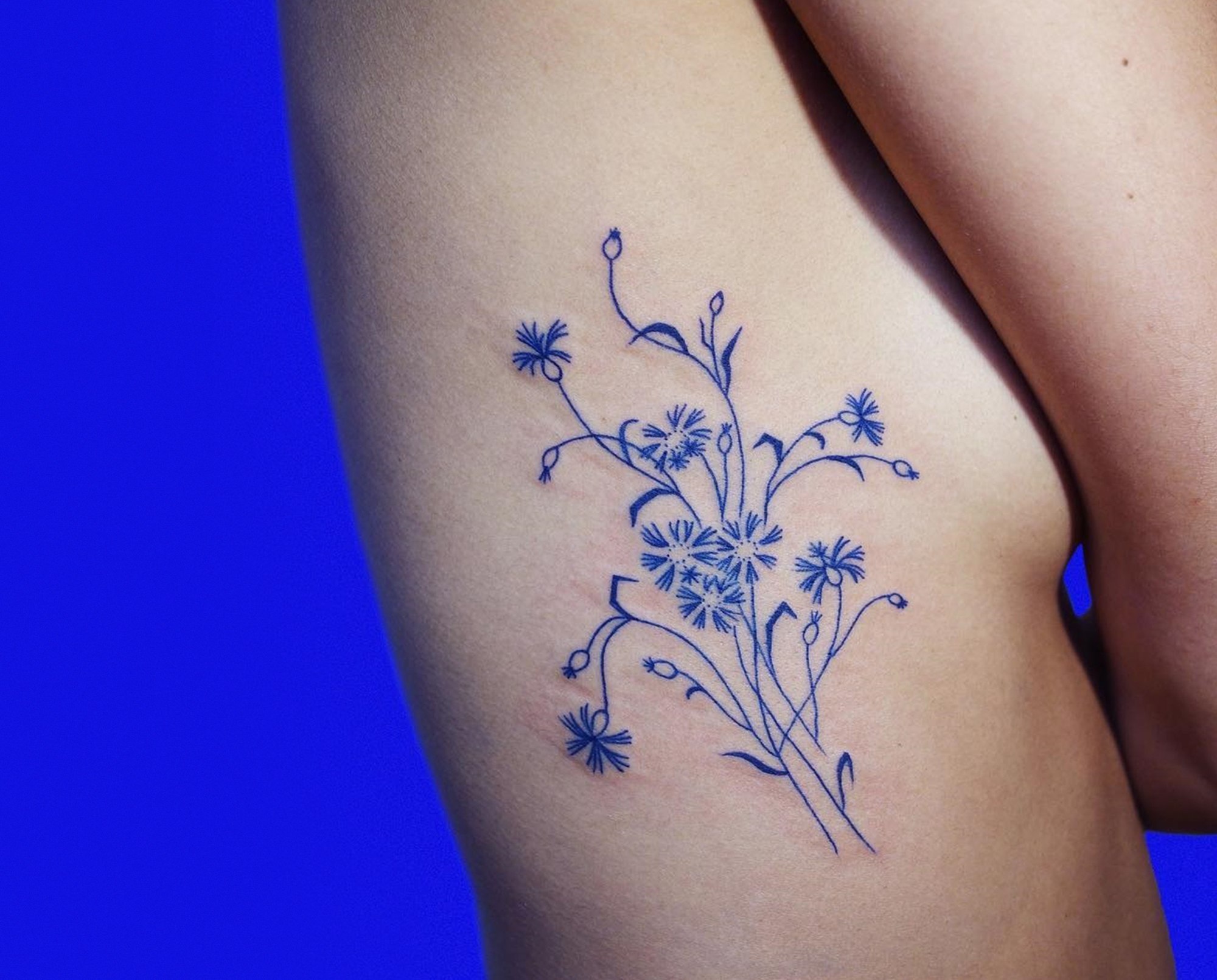 blue flower tattoo on ribs