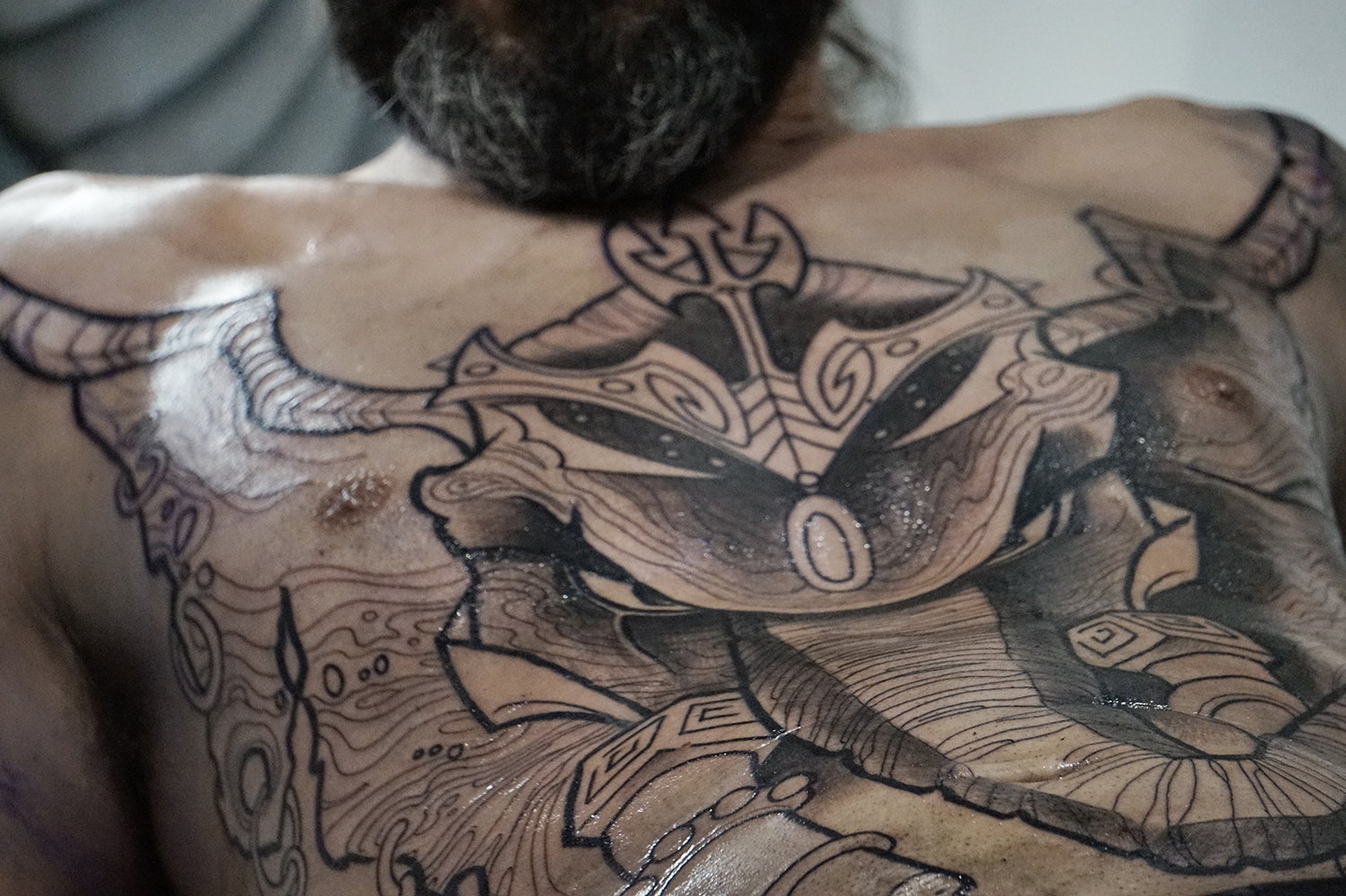 Le tatoueur Alexandre Abreu travaille sur une pièce à large poitrine.