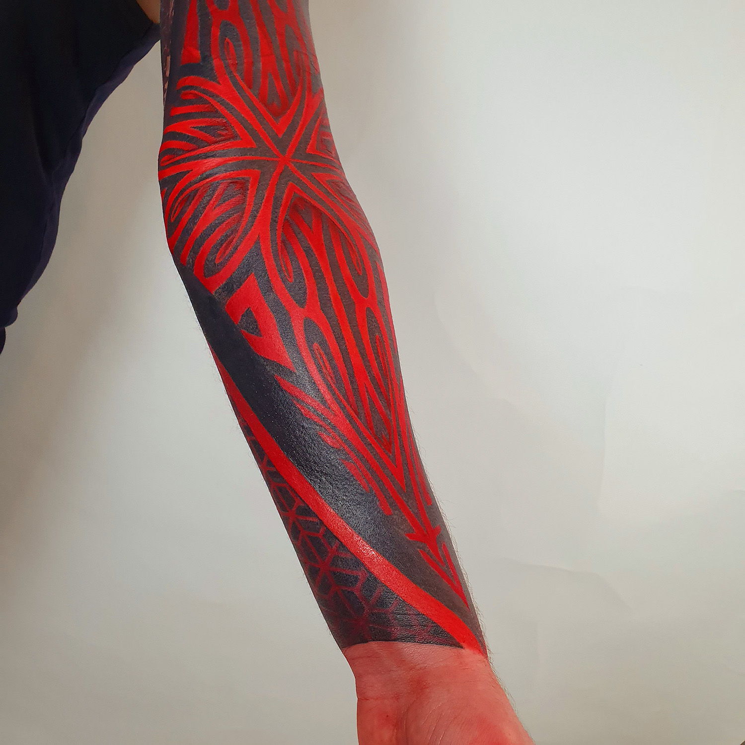 arm sleeve in ornamental, geometric style red and black inks, innovative tattoo