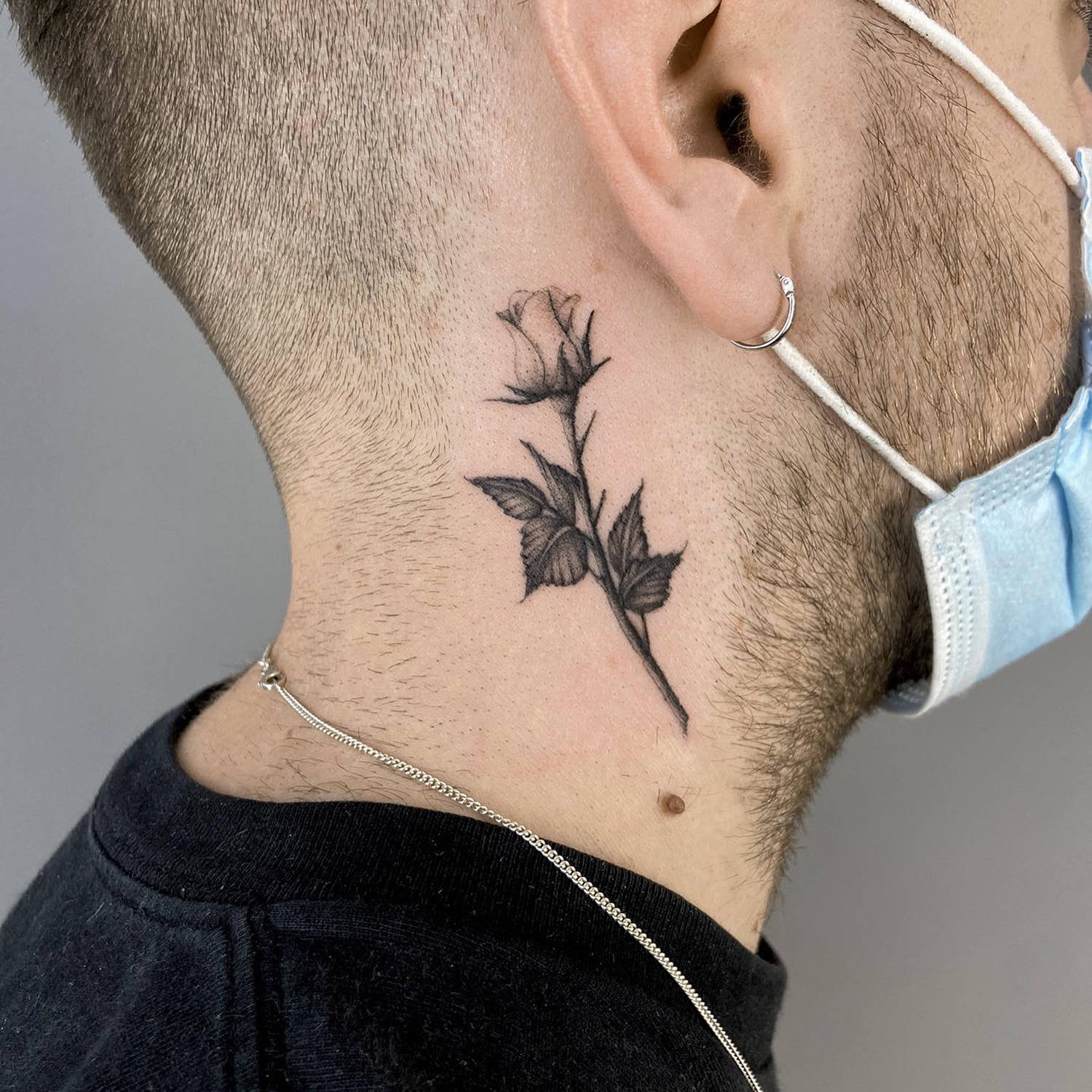 fine-line rose tattoo on neck, black ink