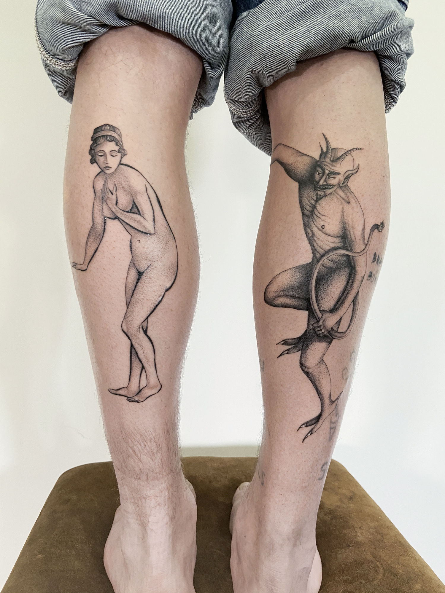 woman and devil tattoo on legs by delphin muquet