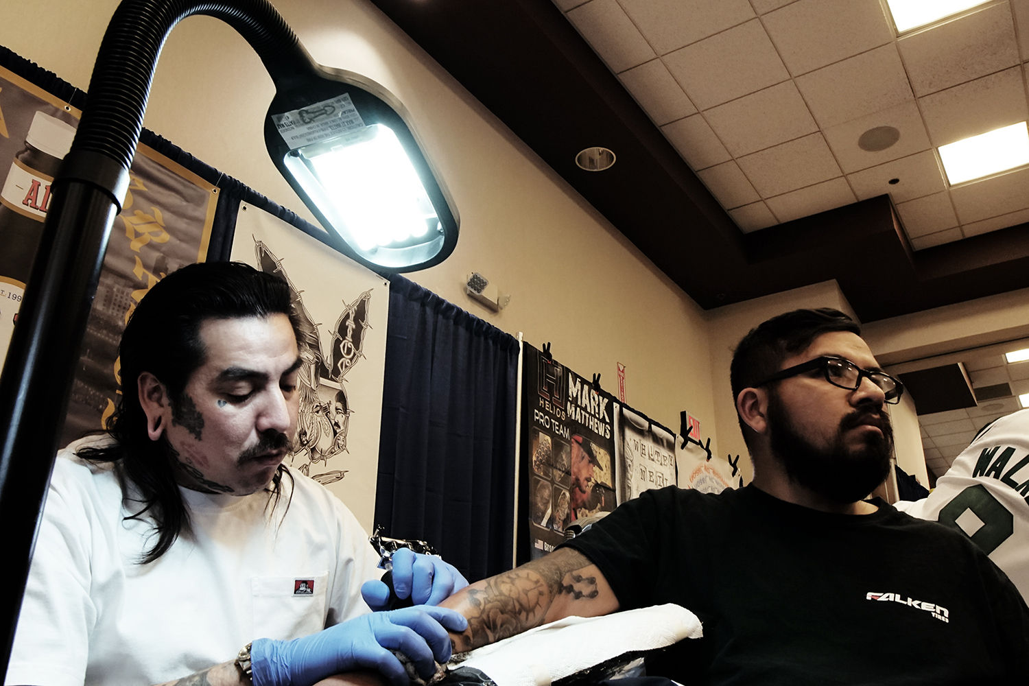 G butch felix tattooing client's arm at tattoo expo at feather falls casino, california