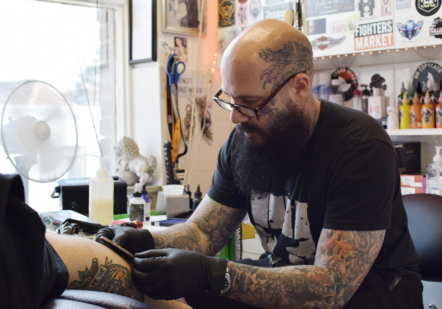 Owner and tattooist Marc Newton, using a coptic tattoo stamp on client, at the Skin Sorcerer