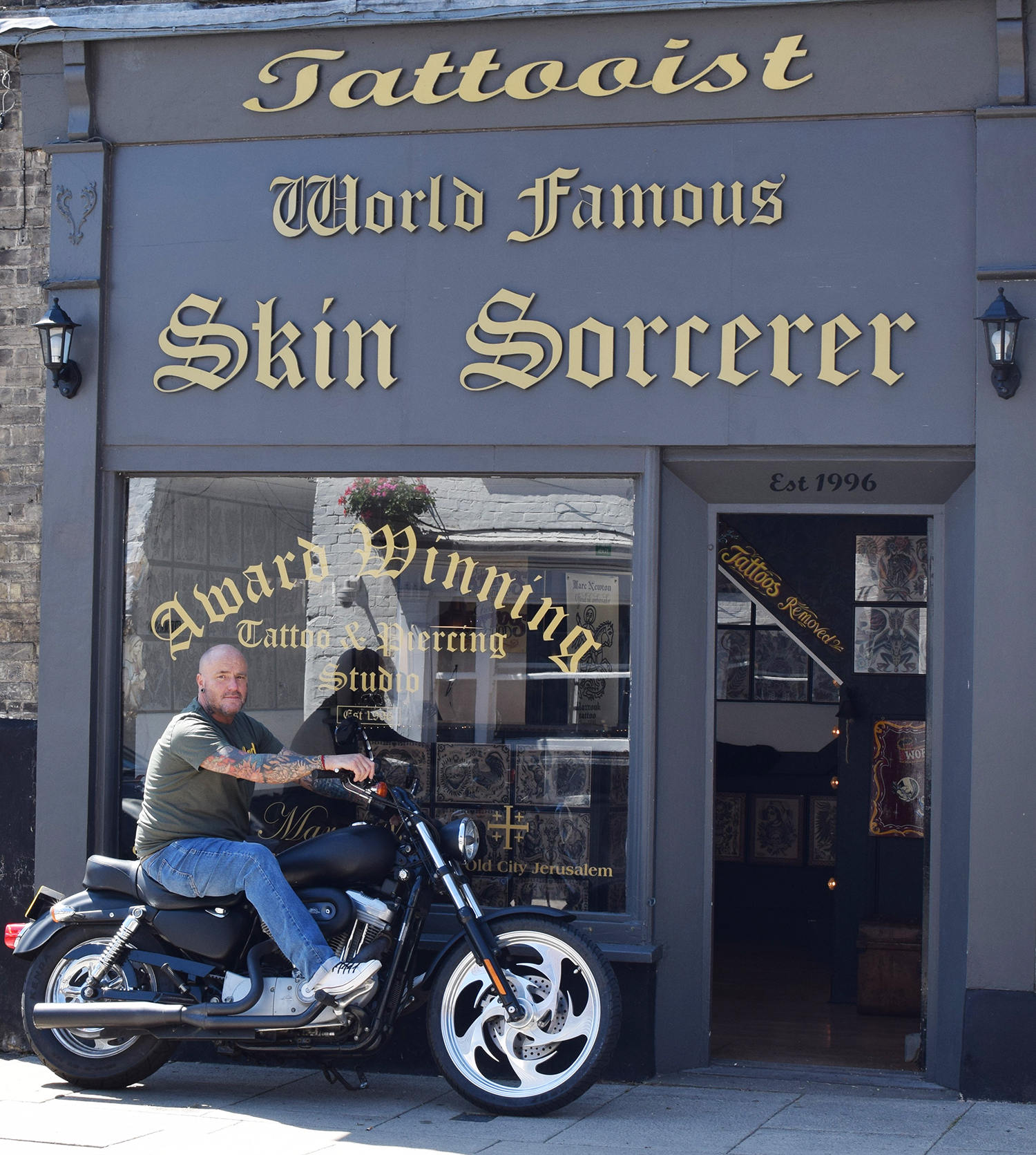 tattoo anthropologist Stephen c stratton on his motorcycle in front of the world famous skin sorcerer tattoo studio