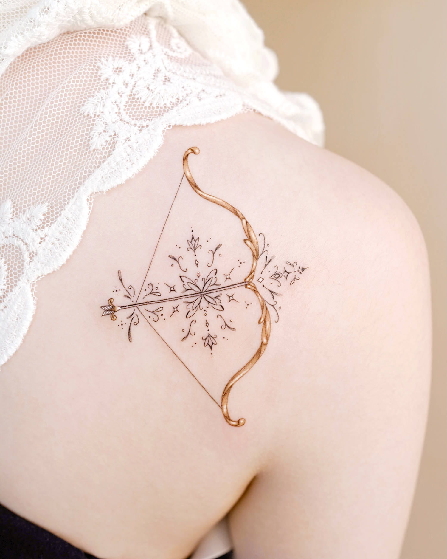 A delicate cross and bow in micro-tattoo style.