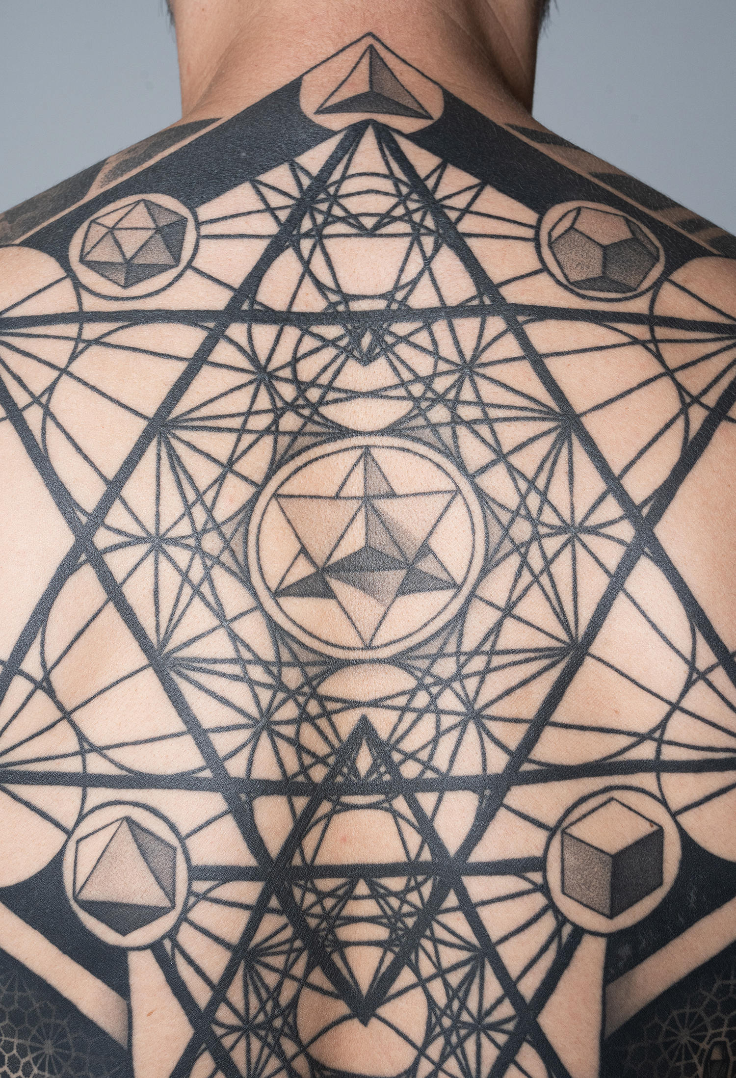 The intricate layering of geometric motifs on back tattoo