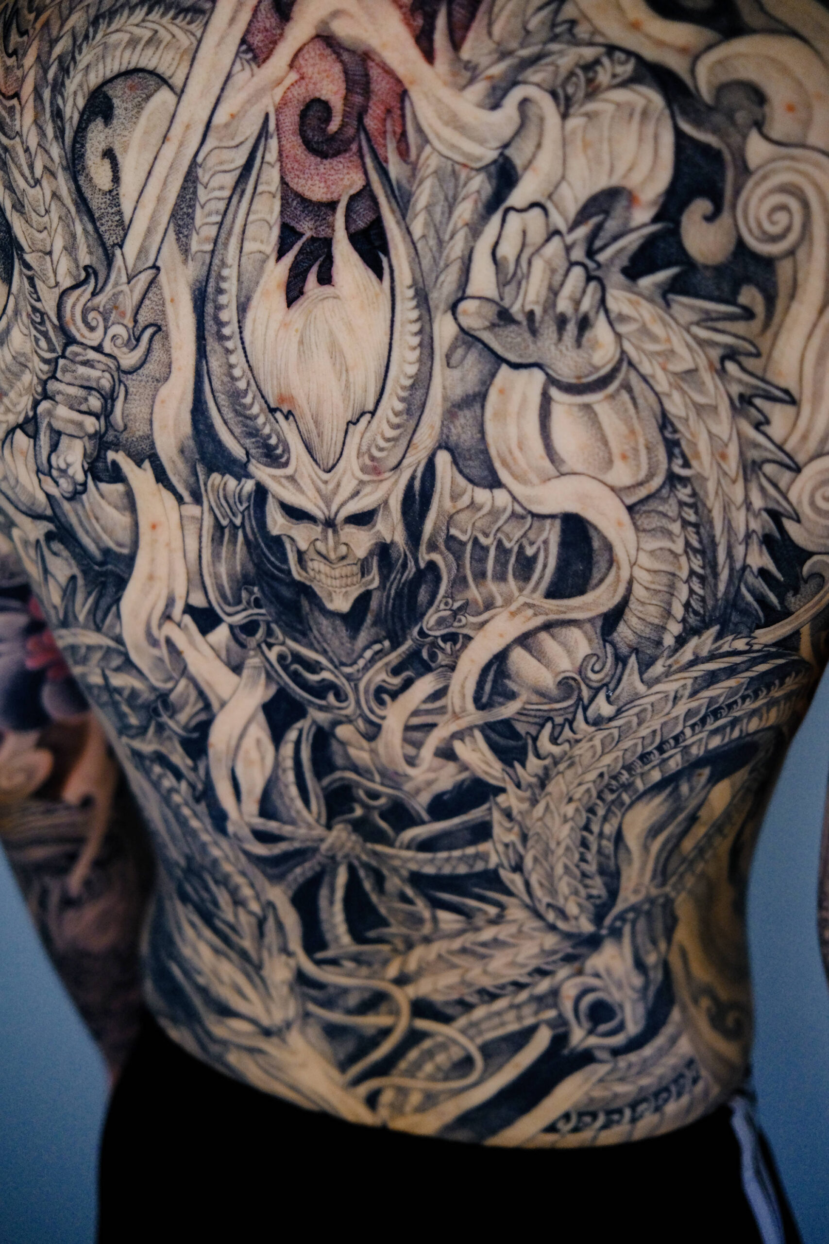 A black and gray tattoo of the Japanese thunder god Raijin