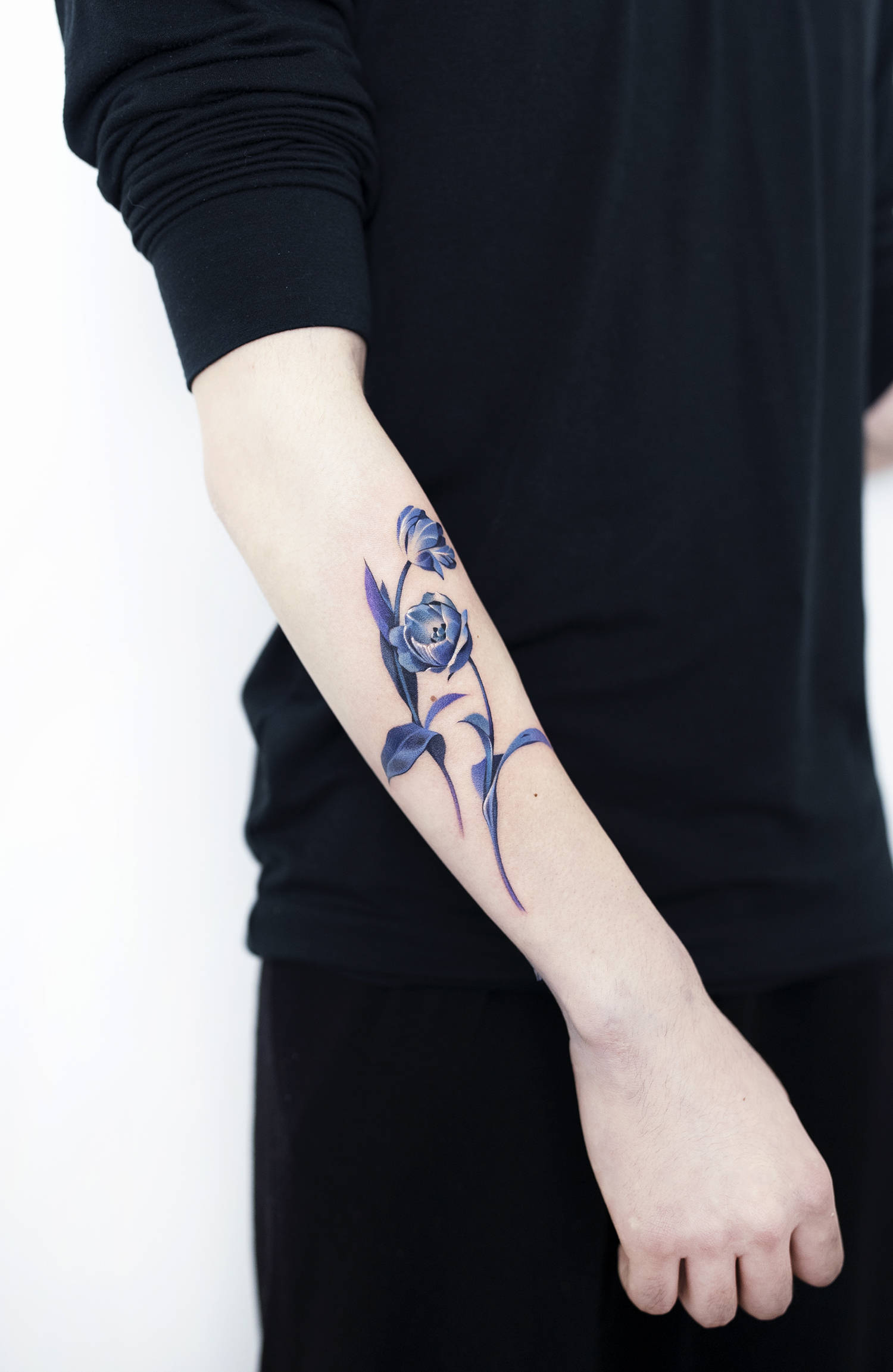 blue flower tattoo on arm, with white highlights
