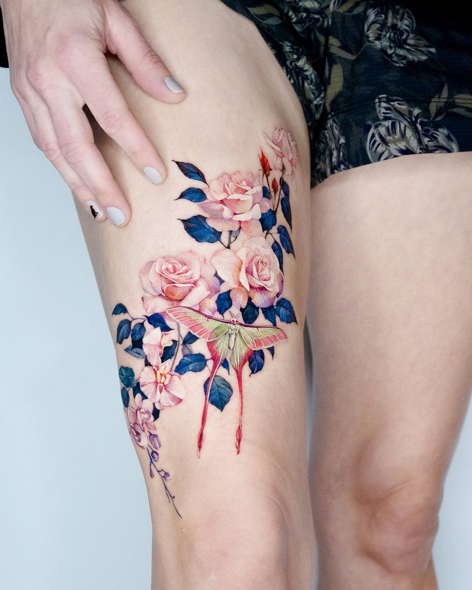 pink roses with wing-insect tattoo on thigh