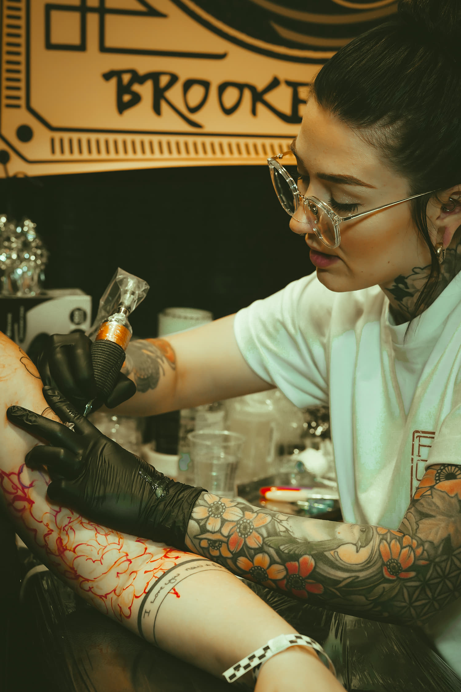 female tattooer Brooke Weeks doing a floral work representing full circle tattoos from San diego photo copyright Adriana de Barros
