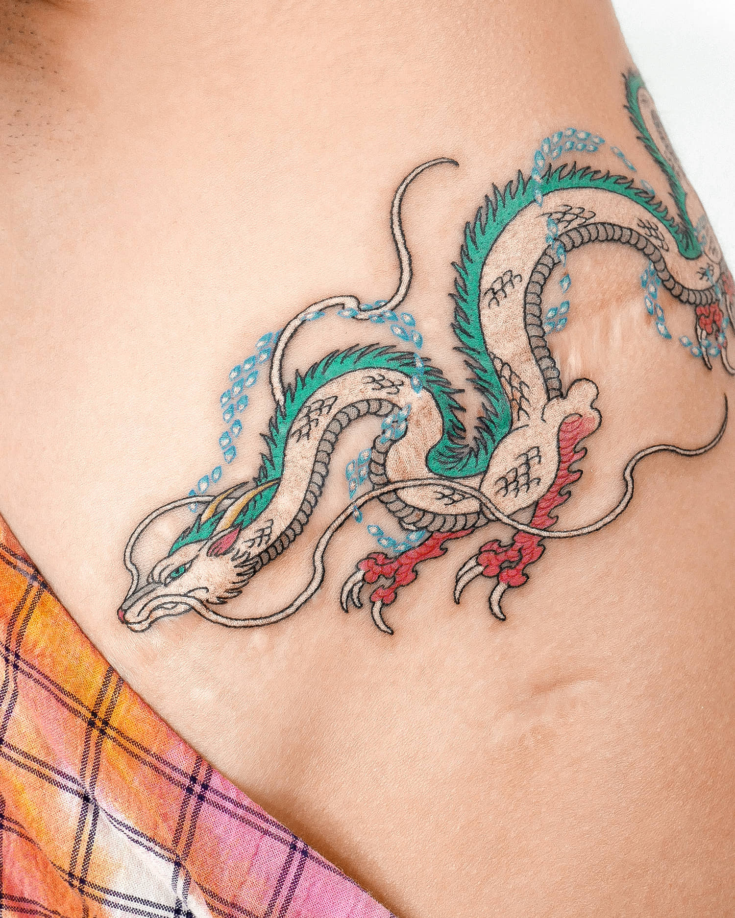 Fantasy dragon in white ink, jade and red tattoo