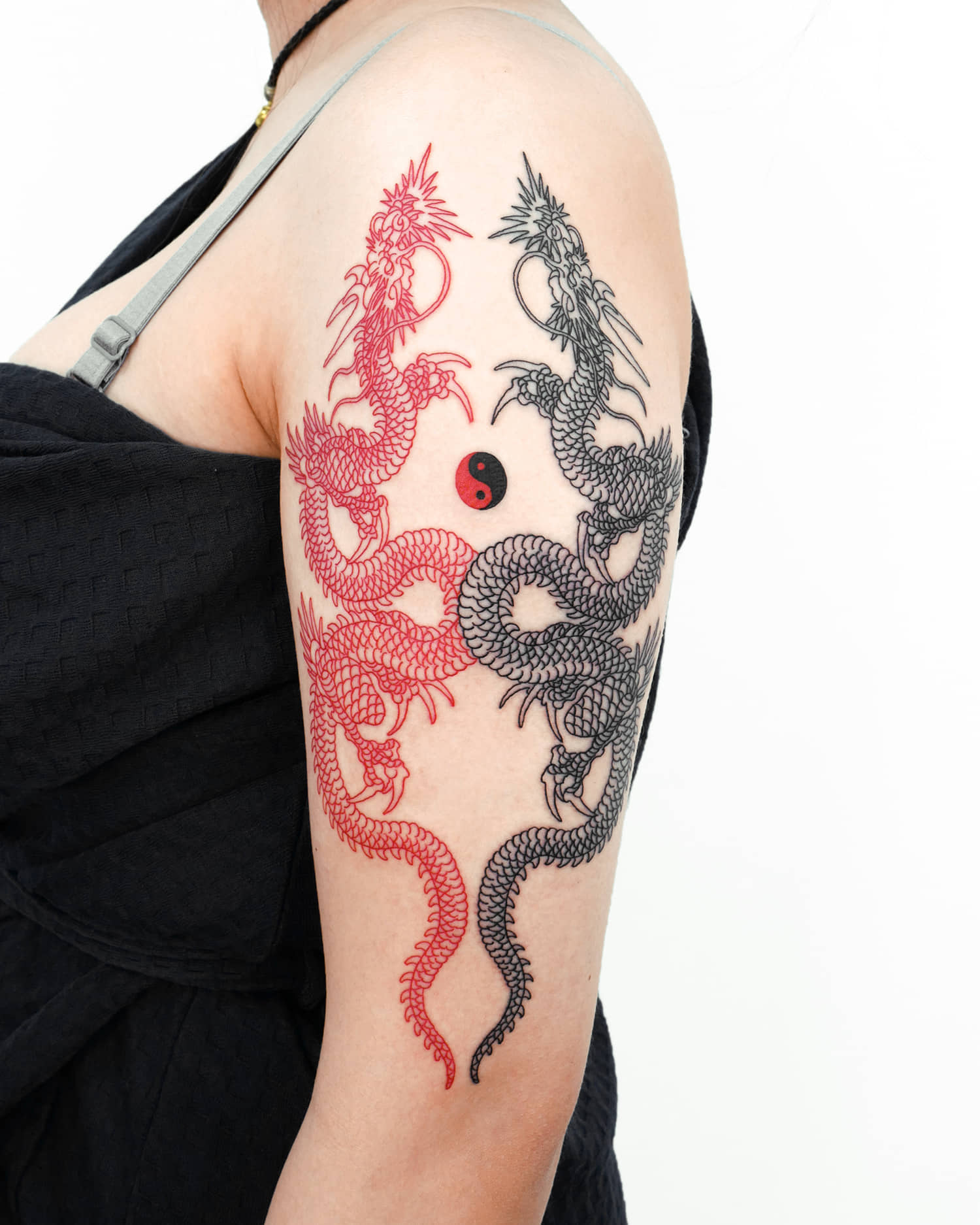 Yin and Yang dragon tattoo on the arm, red and black