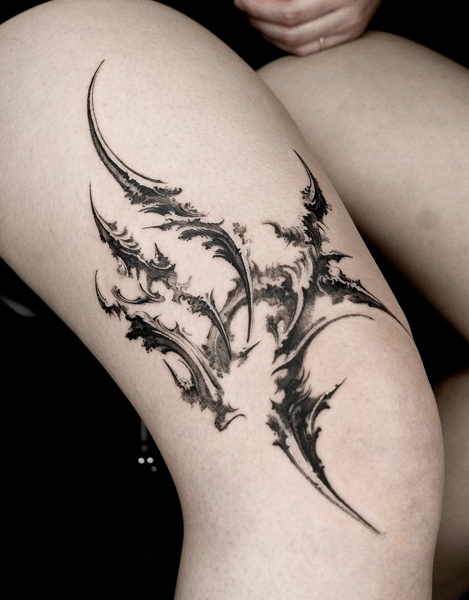 another claw like abstract tattoo on thigh, swishes