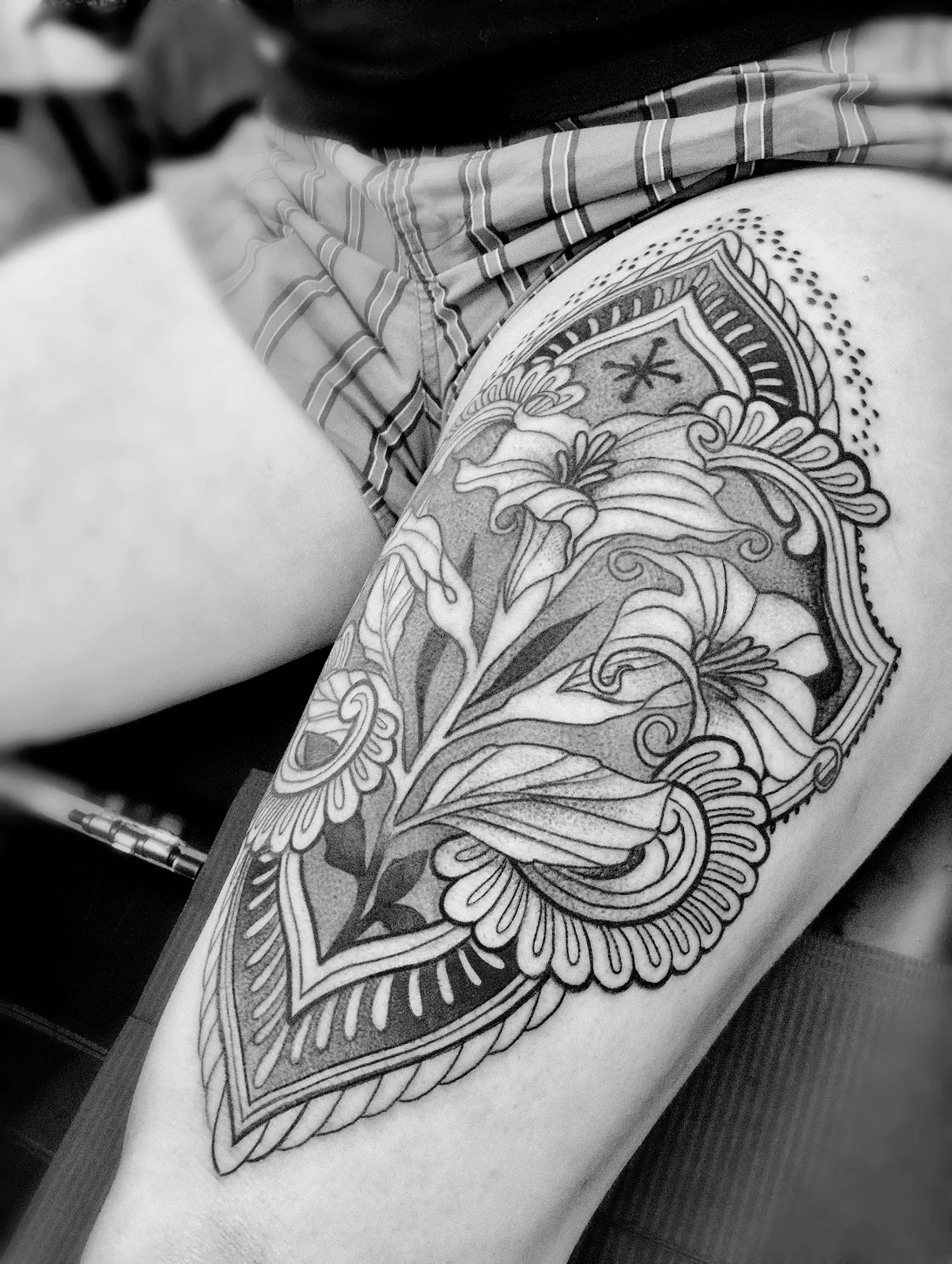 tattoo on thigh, ornamental black work. The client, who is in her fifties, is contemplating the changes she is experiencing and the life she has lived so far. The tattoo depicts three phases of life: childhood, adulthood, and old age, represented by three flower blooms.
