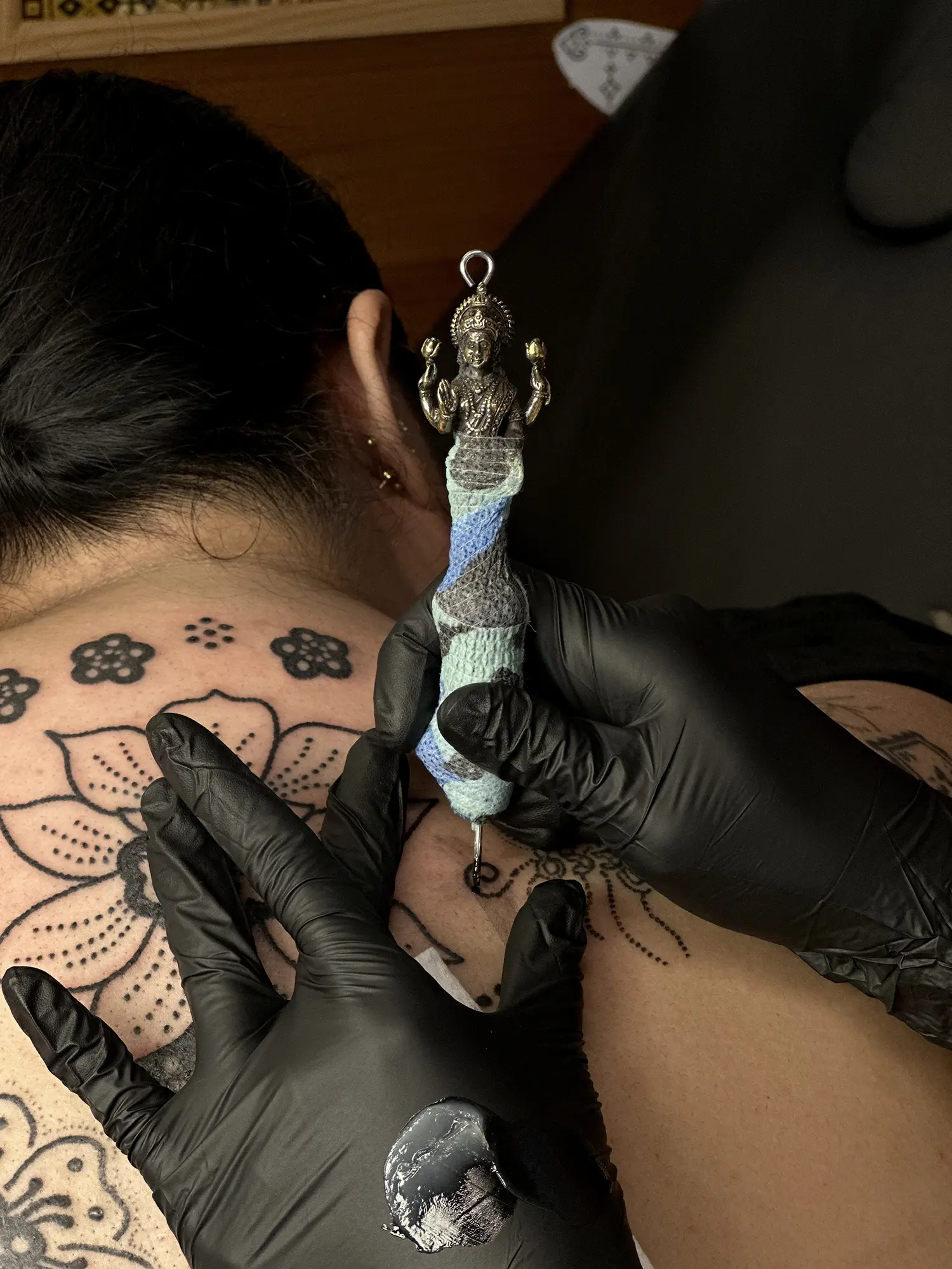 Poke Ahontas applies this handpoke instrument, crafted by Rodolphe Cintorino and depicting Goddess Lakshmi, with a heavier base, which allows for thicker lines