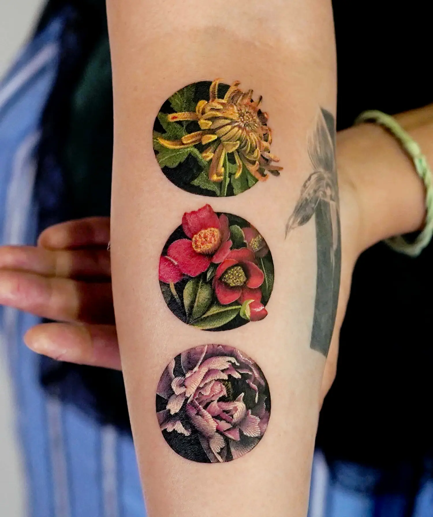 colored flower tattoos in three circles on the arm